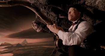 Movie still from “The Imaginarium of Doctor Parnassus” (2009), directed by Terry Gilliam – A man in a white shirt and a red bow tie climbing up a tree; Medium shot, Low angle