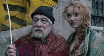 Movie still from “The Imaginarium of Doctor Parnassus” (2009), directed by Terry Gilliam – An old man and a young woman standing next to each other under an umbrella; Close Up shot, Low angle