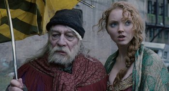 Movie still from “The Imaginarium of Doctor Parnassus” (2009), directed by Terry Gilliam – An old man and a young woman standing next to each other holding an umbrella; Close Up shot, Low angle
