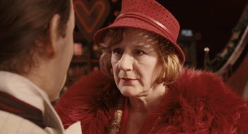 Movie still from “The Imaginarium of Doctor Parnassus” (2009), directed by Terry Gilliam – An older woman wearing a red hat and a fur coat; Close Up shot, Over the shoulder angle