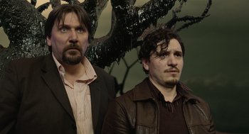 Movie still from “The Imaginarium of Doctor Parnassus” (2009), directed by Terry Gilliam – A couple of men standing next to each other in a room; Medium shot, Low angle