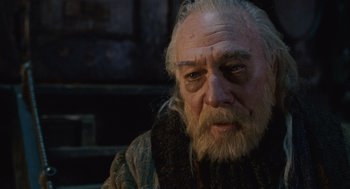 Movie still from “The Imaginarium of Doctor Parnassus” (2009), directed by Terry Gilliam – An old man with a beard and a white beard; Close Up shot, Over the shoulder angle