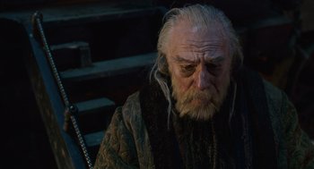 Movie still from “The Imaginarium of Doctor Parnassus” (2009), directed by Terry Gilliam – An old man with a long white beard sitting on steps; Close Up shot, High angle