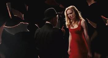Movie still from “The Imaginarium of Doctor Parnassus” (2009), directed by Terry Gilliam – A woman in a red dress talking to a man in a black suit; Medium shot, Over the shoulder angle