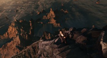 Movie still from “The Imaginarium of Doctor Parnassus” (2009), directed by Terry Gilliam – A man sitting on top of a mountain looking down; Extreme Wide shot, Overhead angle