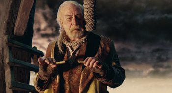 Movie still from “The Imaginarium of Doctor Parnassus” (2009), directed by Terry Gilliam – An old man with a long white beard holding a wooden stick; Medium shot, Low angle