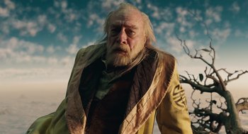 Movie still from “The Imaginarium of Doctor Parnassus” (2009), directed by Terry Gilliam – An old man with long white hair wearing a yellow jacket; Close Up shot, Low angle