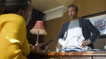 Movie still from “Full Circle” (2023), directed by Steven Soderbergh – A man and a woman are looking at a phone; Medium shot, Over the shoulder angle