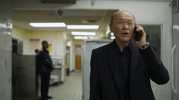 Movie still from “Full Circle” (2023), directed by Steven Soderbergh – An older man wearing a suit talking on a cell phone; Medium shot, Low angle