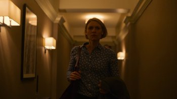 Movie still from “Full Circle” (2023), directed by Steven Soderbergh – A woman holding a bag walking down a hall way; Medium shot, Low angle