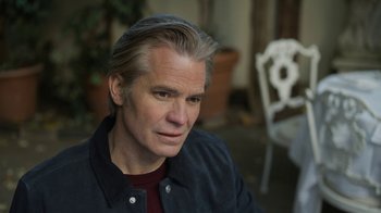 Movie still from “Full Circle” (2023), directed by Steven Soderbergh – A person sitting in front of a chair; Close Up shot, High angle