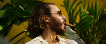 Movie still from “The Infiltrator” (2016), directed by Brad Furman – A person wearing sunglasses and holding a cigar; Close Up shot, Low angle