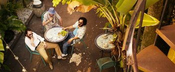 Movie still from “The Infiltrator” (2016), directed by Brad Furman – Two men sitting at a table with plates of food; Wide shot, Overhead angle
