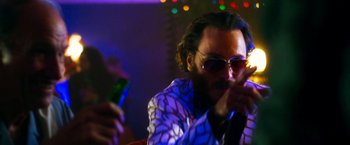 Movie still from “The Infiltrator” (2016), directed by Brad Furman – A man with a beard and sunglasses is drinking a beer; Close Up shot, Low angle