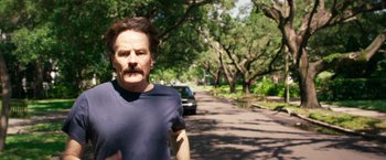 Movie still from “The Infiltrator” (2016), directed by Brad Furman – A man standing on the side of a road near trees; Close Up shot, Over the shoulder angle