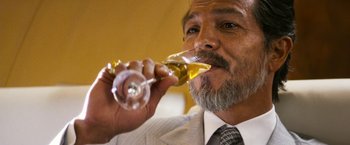 Movie still from “The Infiltrator” (2016), directed by Brad Furman – A man in a suit and tie holding a glass of wine; Close Up shot, Low angle