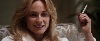 Movie still from “The Infiltrator” (2016), directed by Brad Furman – A woman smiling for the camera; Close Up shot, Over the shoulder angle