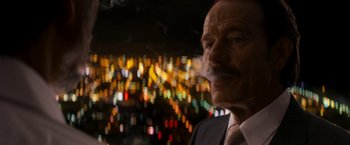 Movie still from “The Infiltrator” (2016), directed by Brad Furman – An older man smoking a cigarette in front of a city skyline at night; Close Up shot, Low angle