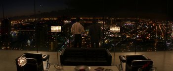 Movie still from “The Infiltrator” (2016), directed by Brad Furman – Two men standing on a couch looking out over a city at night; Extreme Wide shot, Over the shoulder angle