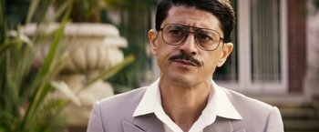 Movie still from “The Infiltrator” (2016), directed by Brad Furman – A person wearing glasses and a suit; Close Up shot, Low angle