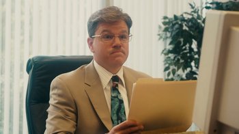 Movie still from “The Informant!” (2009), directed by Steven Soderbergh – A man sitting at a desk holding a paper; Close Up shot, Over the shoulder angle