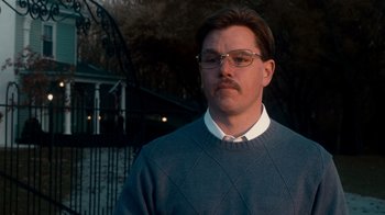 Movie still from “The Informant!” (2009), directed by Steven Soderbergh – A man with a mustache wearing glasses and a sweater; Close Up shot, Low angle
