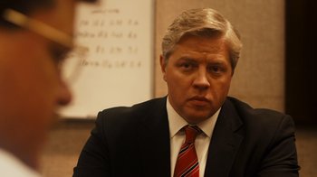 Movie still from “The Informant!” (2009), directed by Steven Soderbergh – A person wearing a suit and tie; Close Up shot, Over the shoulder angle