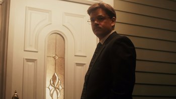 Movie still from “The Informant!” (2009), directed by Steven Soderbergh – A man in a suit and tie standing in front of a door; Medium shot, Low angle