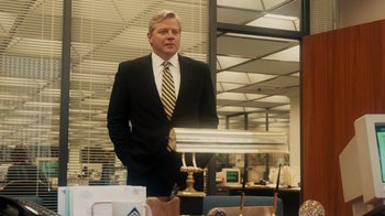 Movie still from “The Informant!” (2009), directed by Steven Soderbergh – A man in a suit and tie standing in an office; Medium shot, Low angle