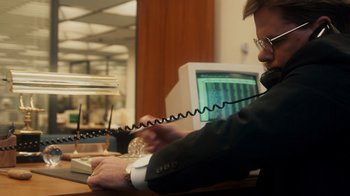 Movie still from “The Informant!” (2009), directed by Steven Soderbergh – A man sitting in front of a computer talking on a phone; Close Up shot, Over the shoulder angle