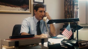 Movie still from “The Informant!” (2009), directed by Steven Soderbergh – A man sitting at a desk talking on a phone; Medium shot, High angle