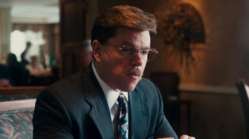 Movie still from “The Informant!” (2009), directed by Steven Soderbergh – A man in a suit sitting at a table; Close Up shot, Over the shoulder angle