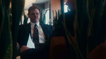 Movie still from “The Informant!” (2009), directed by Steven Soderbergh – A man wearing a suit and tie sitting in a room; Medium shot, Over the shoulder angle