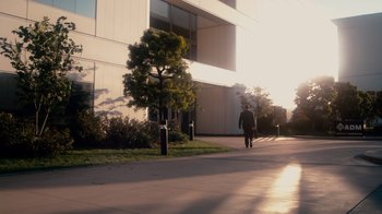 Movie still from “The Informant!” (2009), directed by Steven Soderbergh – A man walking down a sidewalk in front of a building; Extreme Wide shot, Low angle