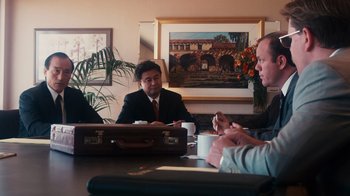 Movie still from “The Informant!” (2009), directed by Steven Soderbergh – A group of people sitting around a table; Medium shot, Over the shoulder angle