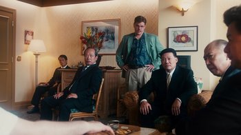 Movie still from “The Informant!” (2009), directed by Steven Soderbergh – A group of men sitting in a living room together; Medium shot, Over the shoulder angle