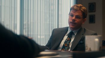 Movie still from “The Informant!” (2009), directed by Steven Soderbergh – A man in a suit and tie sitting at a table; Medium shot, Over the shoulder angle