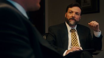Movie still from “The Informant!” (2009), directed by Steven Soderbergh – A man wearing a suit and tie sitting in front of another man in a suit; Close Up shot, Over the shoulder angle