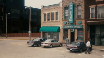 Movie still from “The Informant!” (2009), directed by Steven Soderbergh – Cars are parked in a parking lot in front of a building; Extreme Wide shot, High angle