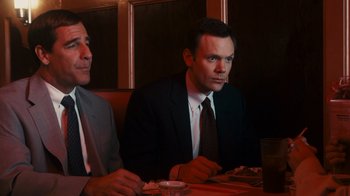 Movie still from “The Informant!” (2009), directed by Steven Soderbergh – Two men sitting at a table in front of a plate of food; Medium shot, Over the shoulder angle