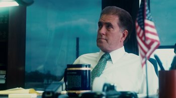 Movie still from “The Informant!” (2009), directed by Steven Soderbergh – A person sitting at a table; Medium shot, Over the shoulder angle