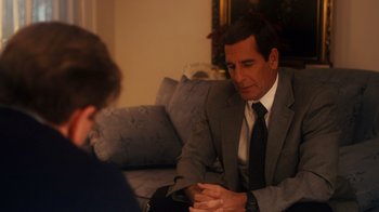 Movie still from “The Informant!” (2009), directed by Steven Soderbergh – A man sitting on a couch talking to another man in a suit; Medium shot, Over the shoulder angle