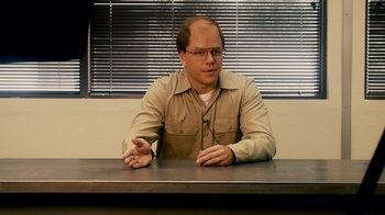 Movie still from “The Informant!” (2009), directed by Steven Soderbergh – A man sitting at a table in front of a window; Medium shot, Over the shoulder angle
