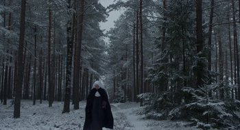 Movie still from “The Innocents” (2016), directed by Anne Fontaine – A person walking in the snow near a forest; Extreme Wide shot, Low angle