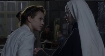 Movie still from “The Innocents” (2016), directed by Anne Fontaine – Two people are standing in a room and one of them is holding a nun's hand; Close Up shot, Over the shoulder angle
