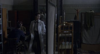 Movie still from “The Innocents” (2016), directed by Anne Fontaine – A woman standing in front of a mirror in a room; Medium shot, Over the shoulder angle