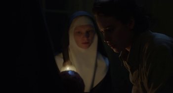 Movie still from “The Innocents” (2016), directed by Anne Fontaine – Two people in a dark room looking at a light; Medium shot, Low angle