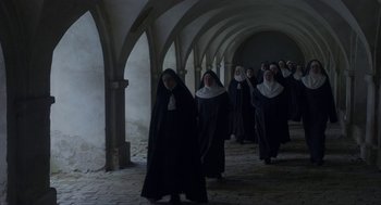 Movie still from “The Innocents” (2016), directed by Anne Fontaine – A group of nuns walking down a brick walkway; Wide shot, High angle