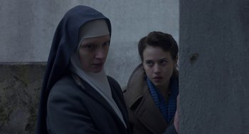 Movie still from “The Innocents” (2016), directed by Anne Fontaine – Two people in a dark room , one of whom is a nun and one of whom is an older woman; Close Up shot, High angle