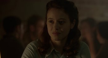 Movie still from “The Innocents” (2016), directed by Anne Fontaine – A young woman is sitting in front of a group of people; Close Up shot, Over the shoulder angle